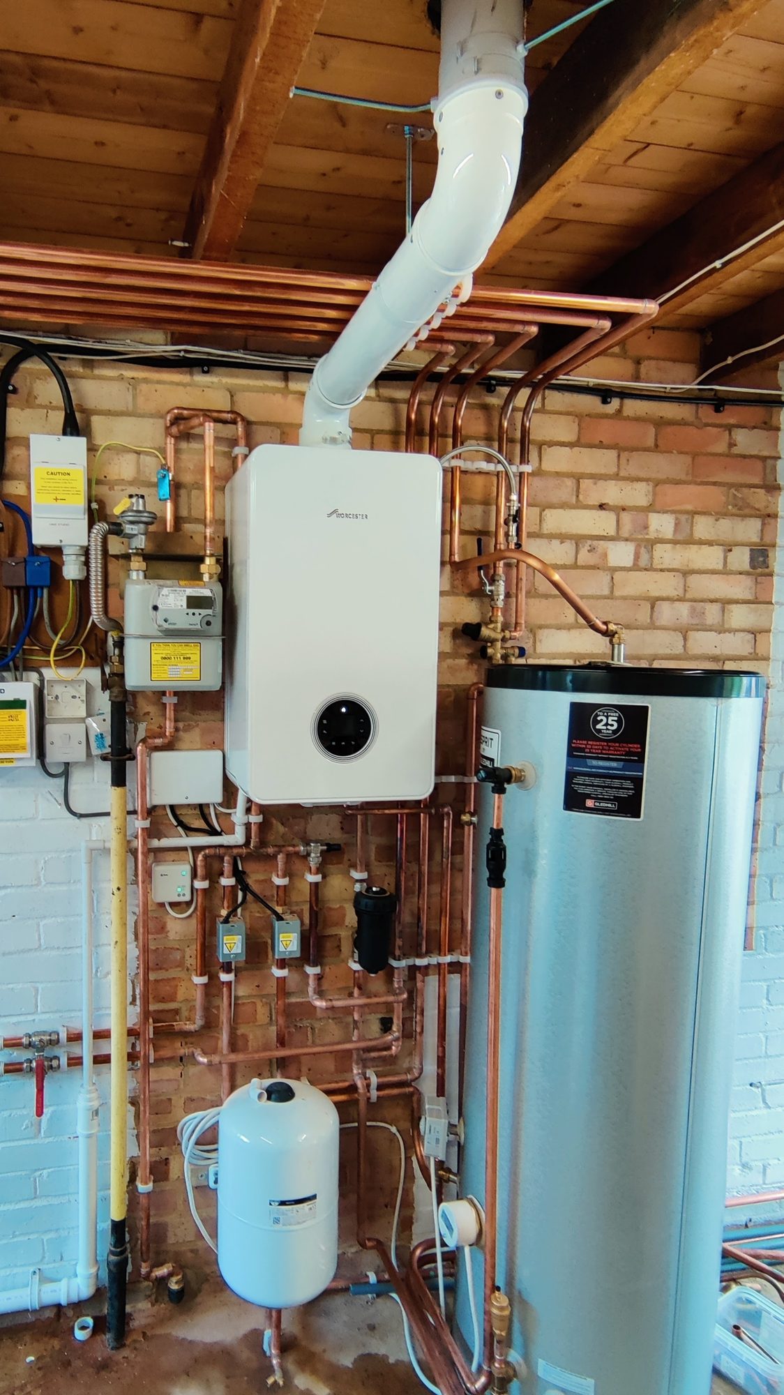 Gas boiler and hot water cylinder installation with copper pipework and expansion vessel in a Surrey utility room