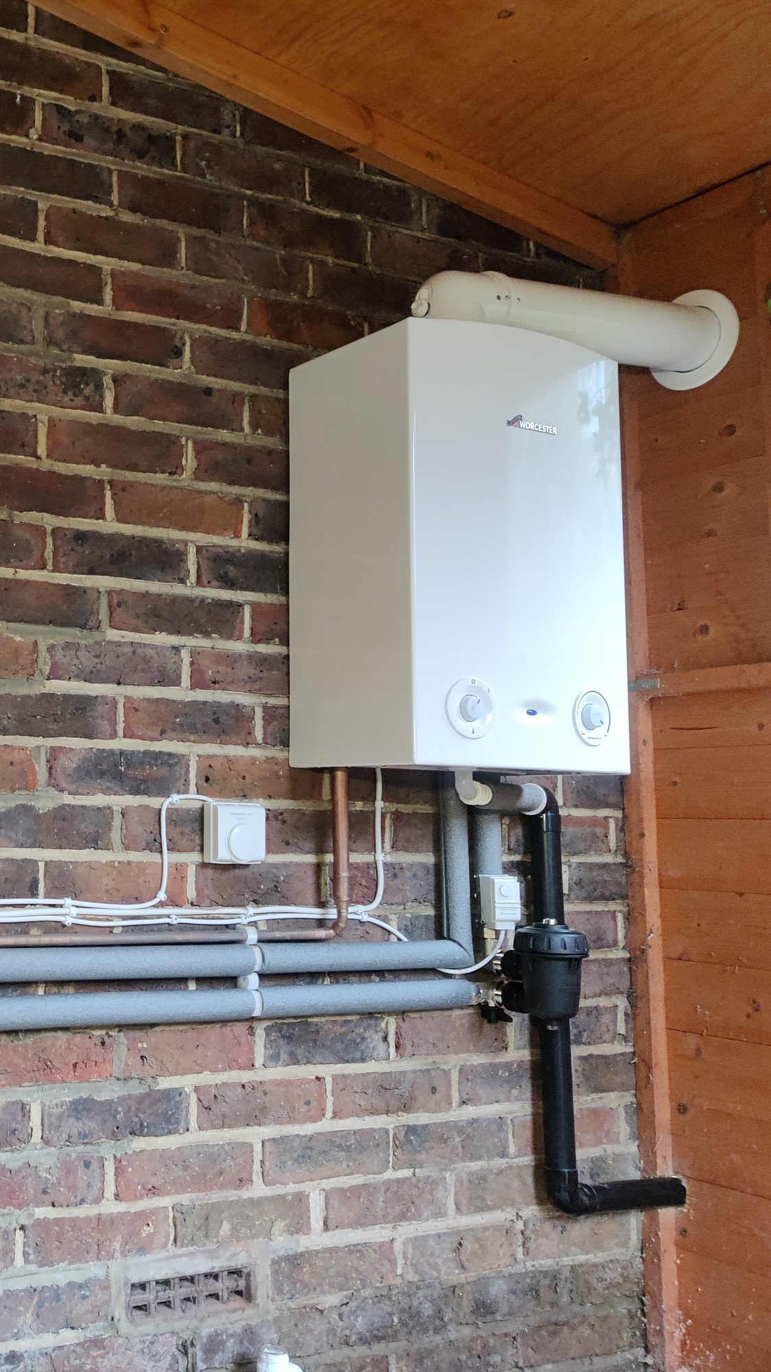 Completed Worcester gas boiler installation on a brick wall with insulated flow and return pipework and a horizontal flue